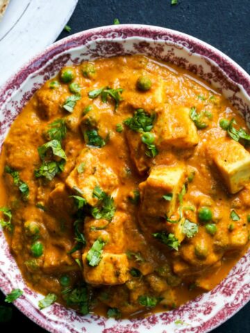 matar paneer in a red and white bowl