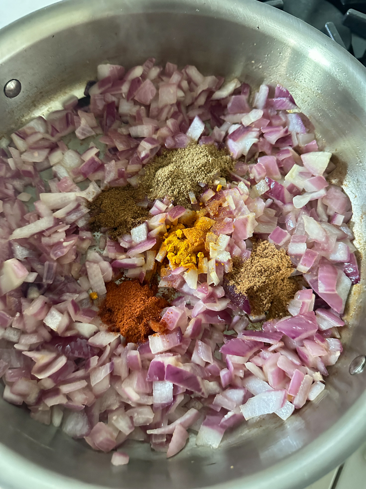spices added to onions in a pan