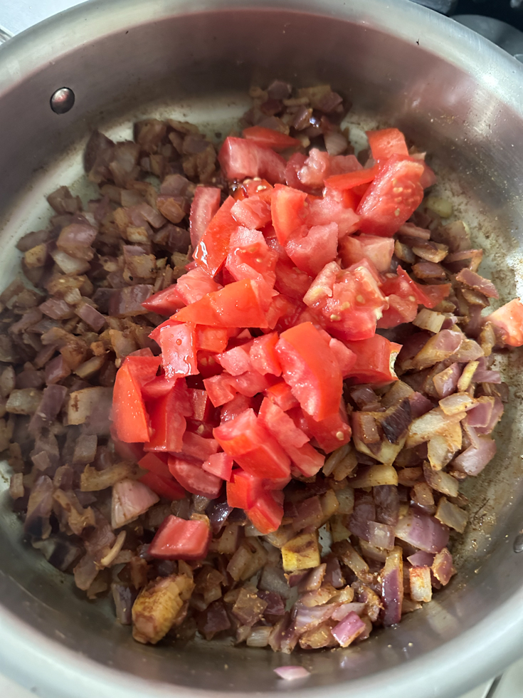chopped tomatoes added to sauteed onions in a pan