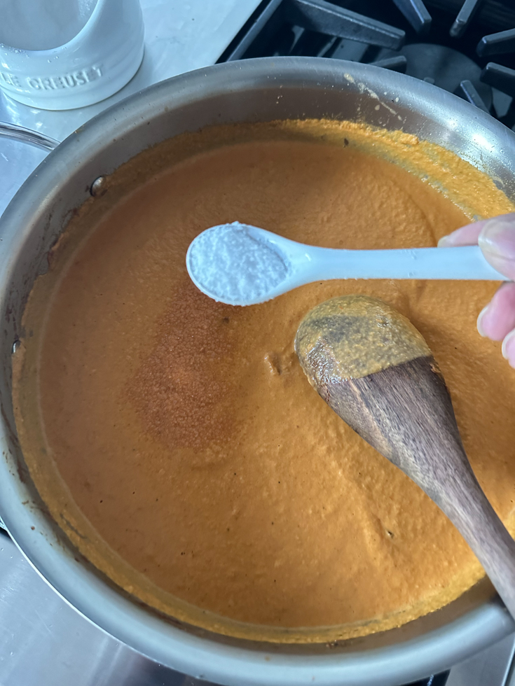 salt being added to the curry in a pan