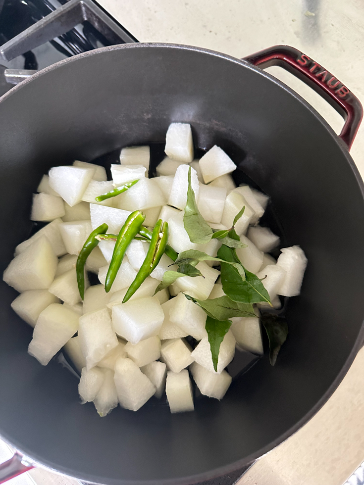 melon, slit green chillies and curry leaves in a pot