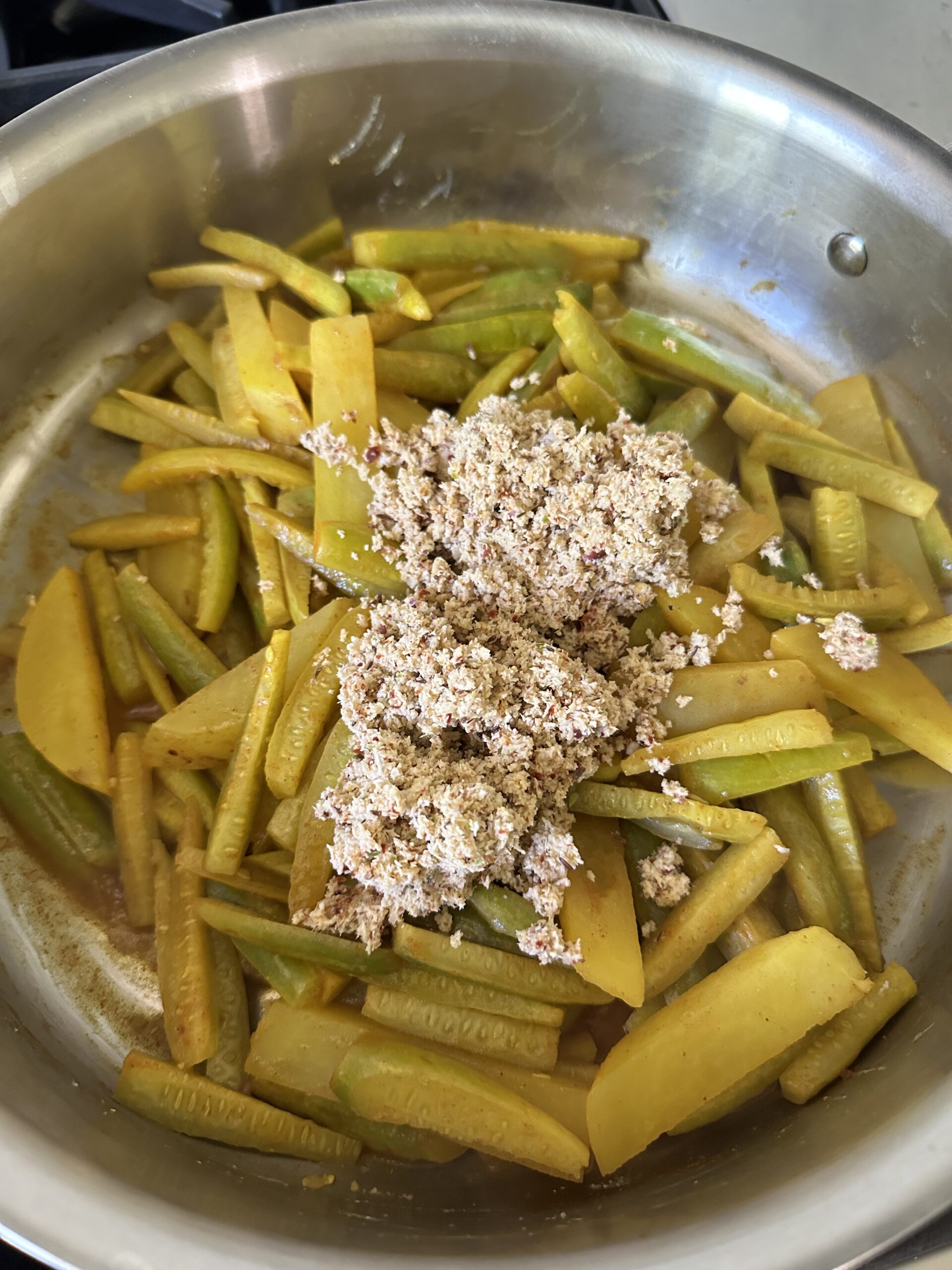 ground coconut with spices added to the cooked veggies in the pan