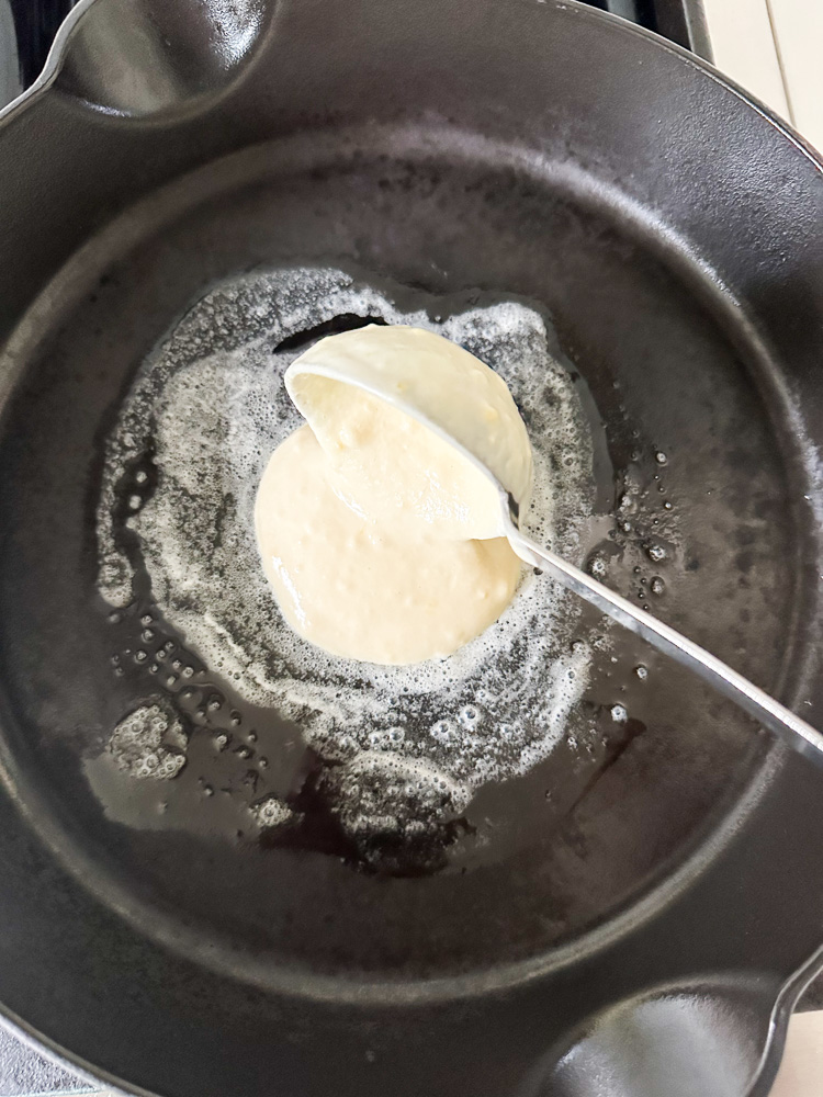 pancake batter being poured on a skillet