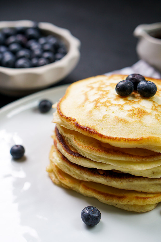 stack of pancakes on white plate with blueberries on top