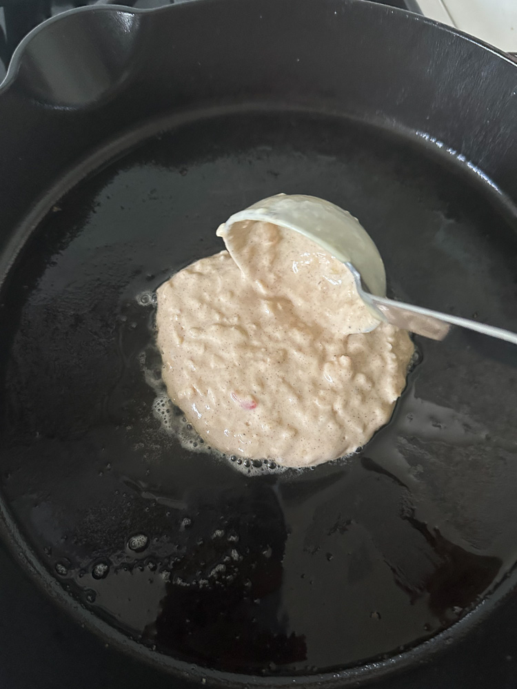 pancake being poured on a greased skillet