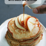 A stack of pancakes with sliced apples and syrup on top with text on the image